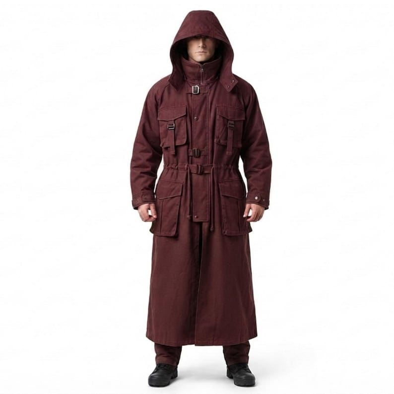 Peut inclure: Un long manteau &agrave; capuche bordeaux fonc&eacute; dot&eacute; d'un col montant, d'une fermeture &eacute;clair frontale et de multiples poches utilitaires &agrave; boucles. Le v&ecirc;tement comprend un cordon de serrage &agrave; la taille et des manches longues &agrave; poignets boutonn&eacute;s.