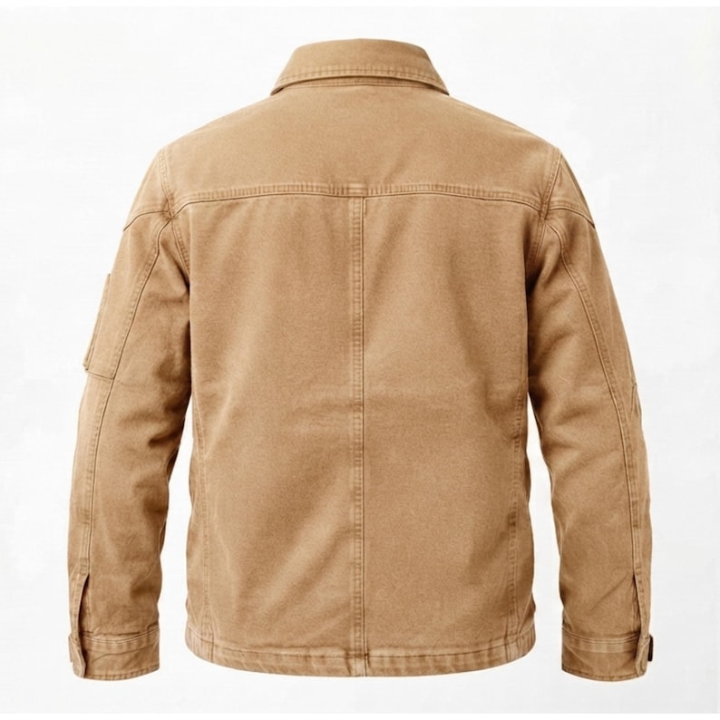 May include: A tan-colored jacket featuring a classic collar, long sleeves with buttoned cuffs, and a structured back panel with vertical stitching. The garment is constructed with durable fabric, showcasing reinforced seams and a clean, uniform finish.