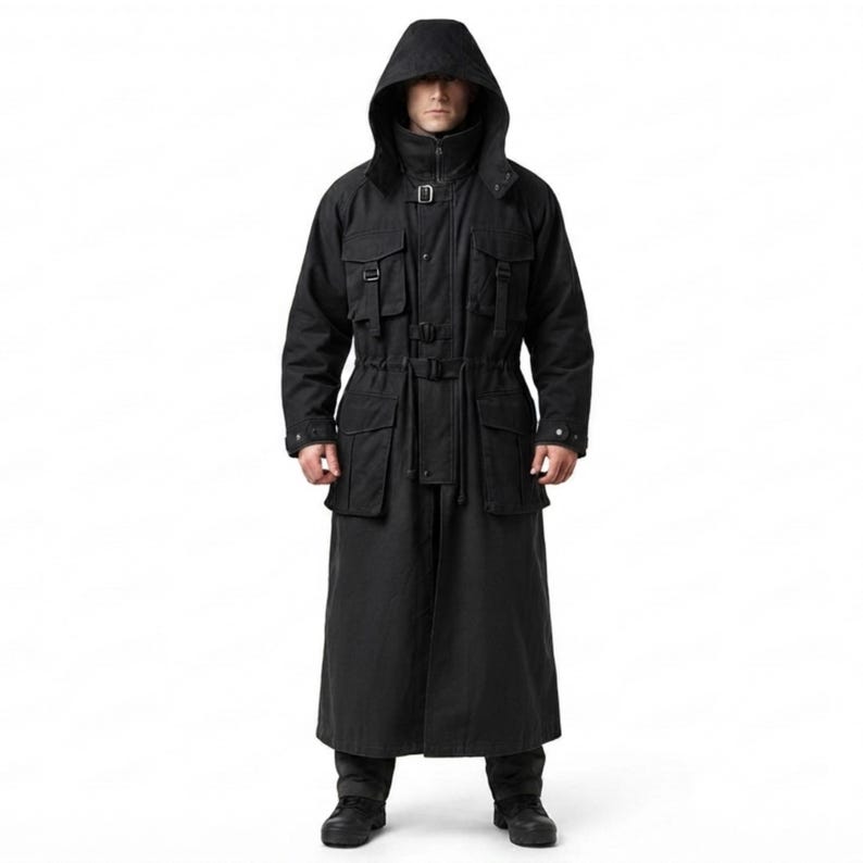 Peut inclure: Un long manteau noir &agrave; capuche dot&eacute; d'un col montant, d'une fermeture &eacute;clair frontale et de multiples poches utilitaires sur la poitrine et les hanches. Le v&ecirc;tement comprend des sangles &agrave; boucle r&eacute;glables &agrave; la taille et &agrave; la poitrine.