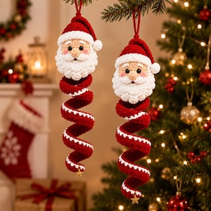 Puede incluir: Dos adornos navideños de ganchillo hechos a mano con forma de Papá Noel y un cuerpo en espiral rojo y blanco. Cada figura tiene una barba blanca, un gorro rojo con un pompón blanco y una pequeña estrella dorada en la base de la espiral.