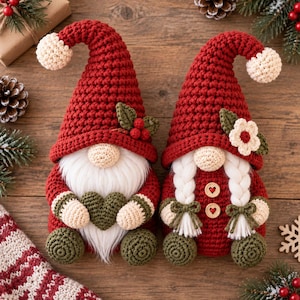 Close-up of a handmade crochet Christmas gnome ornament featuring a tall textured red pointed hat, cream pom-pom, fluffy cream beard, round peach-colored nose, green decorative accents and detailed crochet stitching, shown against festive Christmas greenery.