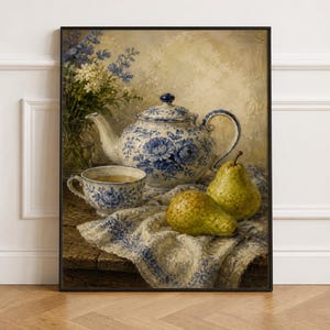 Könnte beinhalten: Ein gerahmtes Stillleben mit einer blau-weiß geblümten Teekanne und passender Teetasse, einer Glasvase mit blau-weißen Blumen und zwei grünen Birnen, die auf einem strukturierten weißen Tuch mit blauem Muster auf einer Holzoberfläche liegen.