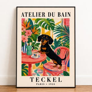 May include: A framed art print titled ATELIER DU BAIN and TECKEL PARIS 1953 featuring a black and tan dachshund standing on a pink chair next to a round pink table with a coffee cup and a green moka pot, surrounded by vibrant tropical plants.