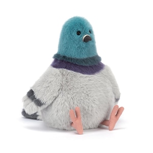 May include: A plush pigeon toy featuring a soft, fuzzy texture with a teal head, a dark purple neck band, and a light grey body. The bird has small black eyes, a dark grey beak, and two light pink, fabric-covered feet extended forward.