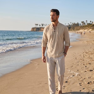 May include: A beige long-sleeved shirt with a lace-up front neckline and matching beige trousers. The shirt features a mandarin collar and sleeves that are rolled up to the elbows. The fabric appears to have a textured, woven finish.