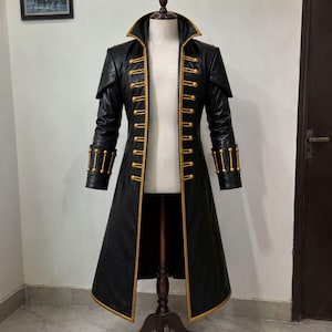 May include: A long black coat featuring a high collar, structured shoulders, and gold-colored trim along the front opening. The garment includes two vertical rows of gold buttons and matching gold-colored bar accents on the cuffs of the sleeves.