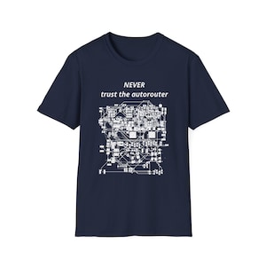 May include: A dark navy blue short-sleeved t-shirt featuring a white graphic print of a complex electronic circuit board diagram. Above the circuit design, the text reads NEVER trust the autorouter in a clean, white, sans-serif font.
