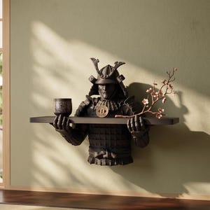 May include: A dark brown wall-mounted shelf featuring a sculpted samurai bust. The samurai figure wears a traditional helmet and armour, with hands extended forward to support the flat shelf surface. A small dark bowl and a branch are on the shelf.