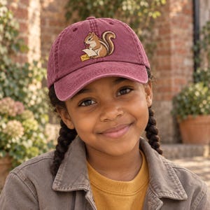 Peut inclure: Une casquette de baseball marron avec une broderie représentant un tamia marron et blanc tenant une enveloppe blanche avec un sceau jaune. La casquette présente une calotte structurée, une visière incurvée et une texture de tissu vieillie.