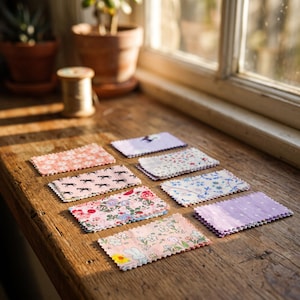 May include: A collection of eight rectangular fabric swatches with pinked edges, featuring various patterns including floral prints, small horse silhouettes, white polka dots on lavender, and a whimsical bunny design in soft pastel color palettes.