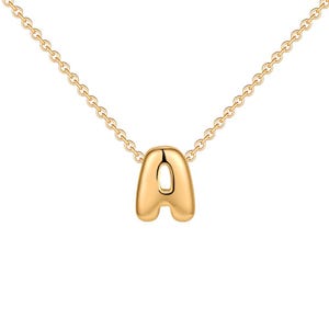 Può includere: Una collana color oro con un ciondolo a forma di lettera A gonfia e lucida, sospeso a una delicata catenina a maglie. Il ciondolo presenta una superficie liscia e arrotondata con una finitura riflettente, e la catena si collega alla parte superiore.