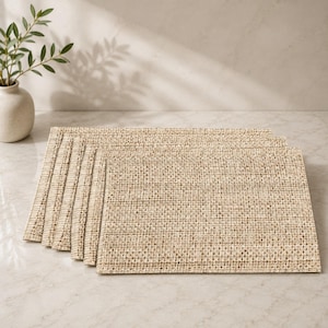 May include: A set of rectangular placemats featuring a woven texture in a neutral beige and tan color palette. The placemats are arranged in a slightly overlapping stack, showcasing the consistent grid-like pattern of the woven material.