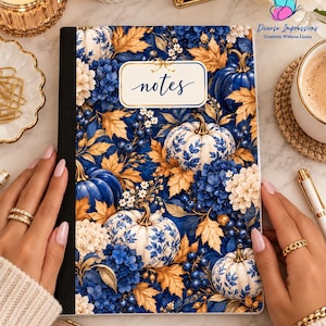 May include: A rectangular notebook with a black spine and a cover featuring a pattern of blue and white pumpkins, blue berries, and golden autumn leaves. A central white label with a gold border contains the handwritten-style text notes.