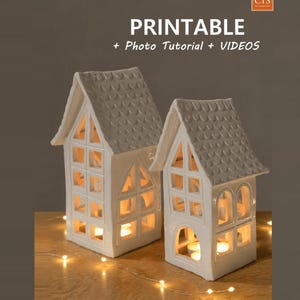 May include: Two white ceramic house-shaped candle holders with shingled roofs and open window cutouts. The text PRINTABLE + Photo Tutorial + VIDEOS is displayed above the houses, with a small CTS logo in the top right corner.