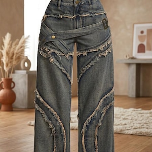 Op de afbeelding: High-waisted wide-leg spijkerbroek in een medium blauwe wassing met een distressed afwerking en rafelige randen langs de naden. De broek heeft een decoratief wikkeldetail bij de taille met een metalen knoop en een gesp aan de zijkant.