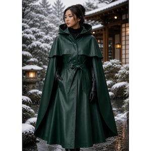 May include: A dark forest green hooded cape coat featuring a smooth finish, a structured hood, a button-front closure, and a matching tie-waist belt. The garment includes long sleeves, a layered cape overlay across the shoulders, and a full-length skirt.