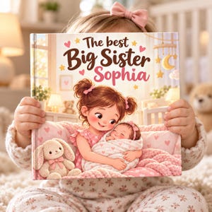 Könnte beinhalten: Ein Kinderbuch mit festem Einband und dem Titel The best Big Sister Sophia, das eine Illustration eines Kindes zeigt, das ein gewickeltes Neugeborenes, einen Plüschhasen und rosa Herzakzente vor einem warmen Hintergrund hält.
