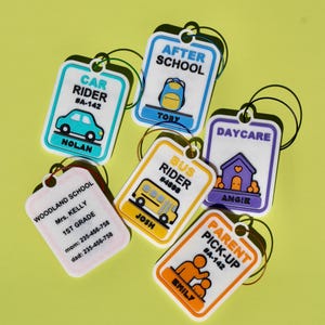 May include: A collection of six rectangular plastic bag tags with rounded corners and wire loops. Each tag features colorful icons and text including Car Rider, After School, Bus Rider, Daycare, Parent Pick-up, and school contact information.