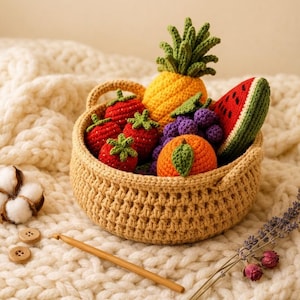 Puede incluir: Una cesta redonda de ganchillo color canela llena de varias frutas tejidas, incluyendo una piña amarilla, fresas rojas, uvas moradas, una naranja y una rodaja de sandía. La cesta cuenta con dos asas pequeñas y un patrón de punto texturizado.