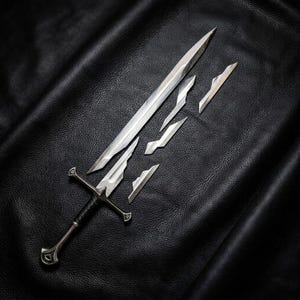 Op de afbeelding: Een zilverkleurig metalen zwaard met een zwart omwikkeld handvat en een pareerstang, vergezeld van vier afzonderlijke, losse bladsegmenten van verschillende groottes die in een rij rechts van het hoofdblad zijn geplaatst.