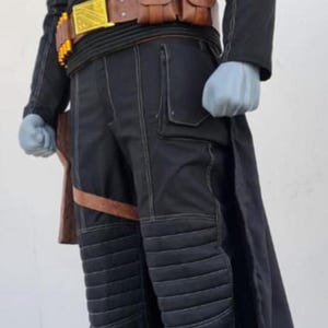 May include: A black long-sleeved tunic and matching trousers featuring white contrast stitching, a high collar, and quilted knee panels. The outfit includes a brown utility belt with pouches, a gold-colored buckle, and a brown leg holster strap.