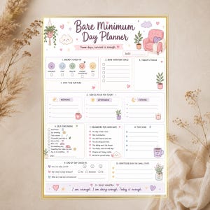 Peut inclure: Une feuille de Bare Minimum Day Planner avec une bordure dorée, comprenant des sections pour le suivi de l'énergie, les objectifs, le plan quotidien, les soins personnels, les rappels, les petites victoires et un mantra en texte violet.