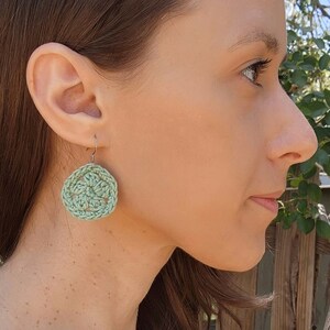 Side profile of a woman wearing a green crochet flower earring.