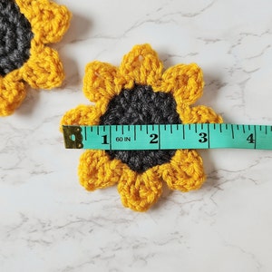 Tape measure across crochet sunflower shows a measurement of about 3.25 inches.
