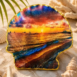 May include: A decorative scallop shell featuring a vibrant sunset ocean scene with silhouettes of sailboats on the horizon. The shell has a glossy finish and is trimmed with a metallic gold edge, highlighting the natural curves of the shell.