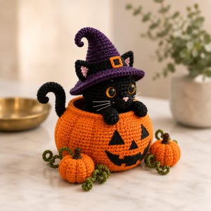 May include: A black crocheted cat wearing a purple witch hat with a yellow buckle, sitting inside a large orange crocheted jack-o'-lantern. Two smaller orange crocheted pumpkins with green curly vines are positioned in front of the main pumpkin.