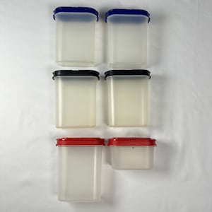 May include: A set of six rectangular storage containers made of translucent plastic. Two containers have blue lids, two have black lids, and two have red lids. The containers vary in height, with five tall units and one shorter, wide unit.