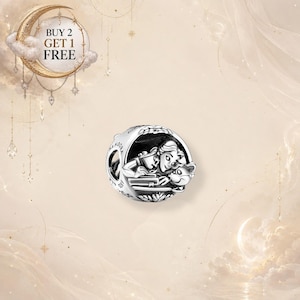 Può includere: Un charm Pandora in argento con una scena incisa che raffigura un personaggio che legge un libro con un piccolo compagno. Il lato del charm è marchiato con il nome del brand Pandora e il punzone S925. L'immagine include il testo BUY 2 GET 1 FREE.