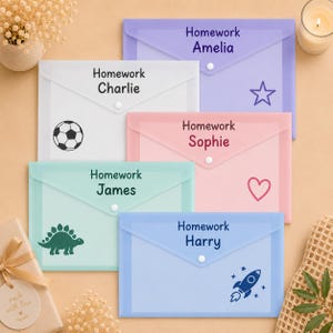 May include: Five rectangular plastic document folders with snap closures, each personalised with the text Homework followed by a name: Amelia, Charlie, Sophie, James, or Harry. Each folder features a unique graphic: a star, football, heart, dinosaur, or rocket ship.