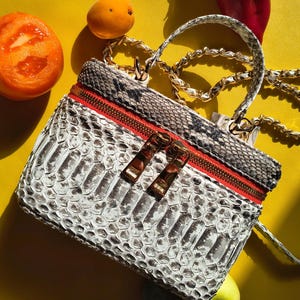 Bolso bandolera de auténtica piel de serpiente, neceser de lujo en blanco y negro, herrajes dorados.