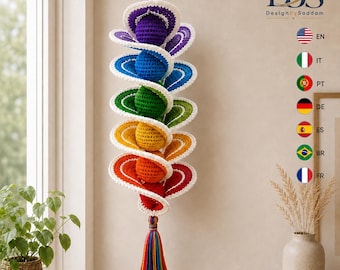 Puede incluir: Una decoración de ganchillo en espiral colgante que presenta una secuencia vertical de esferas en colores del arcoíris, incluyendo morado, azul, verde, amarillo, naranja y rojo. Cada esfera está rodeada por una espiral con borde blanco y una borla.