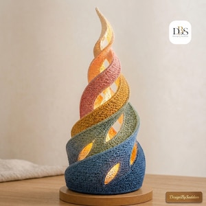 May include: A spiral-shaped table lamp featuring a textured, crocheted exterior with a gradient color scheme transitioning from dark blue at the base to light yellow at the top. The lamp emits a warm internal glow through its open, twisted design.