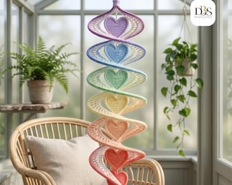 May include: A hanging spiral decoration featuring a series of crocheted hearts in a gradient of colors including purple, blue, green, yellow, orange, and red. The structure is suspended from a single loop at the top, creating a vertical display.