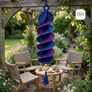 May include: A spiral-shaped crochet hanging decoration featuring a gradient of blue and purple yarn. The piece includes a top loop, leaf-like accents, and a central wooden heart bead at the bottom, finished with a blue and purple yarn tassel.