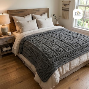 May include: A dark gray chunky crochet blanket with a square grid pattern and a textured border, draped over a bed with light beige bedding, featuring a logo in the corner with the text DBS Design-Season in a white rounded square.