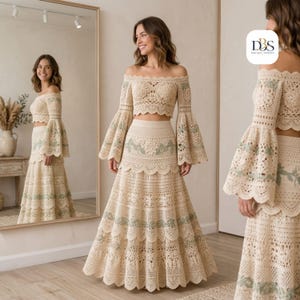 May include: A two-piece crochet set in cream featuring an off-the-shoulder crop top with bell sleeves and a matching tiered maxi skirt. The garment is detailed with intricate lace patterns and subtle sage green floral embroidery throughout.