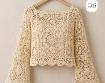 Puede incluir: Una blusa de ganchillo de color crema con mangas largas que presenta un intrincado patrón de mandala circular en la parte delantera y trasera, un escote cuadrado y mangas acampanadas anchas con un dobladillo festoneado. Incluye un logo DBS en la percha.