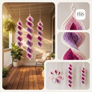 May include: Three hanging spiral ornaments made of crocheted yarn in a gradient of white, light pink, and deep magenta. The ornaments feature a twisted, helical structure with a loop at the top for suspension. The logo DBS Design-Button is visible.