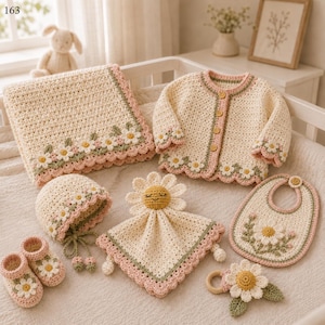 Puede incluir: Un conjunto de ganchillo para bebé que incluye una manta color crema, cárdigan de manga larga con botones de madera, gorro, mantita de seguridad con cabeza de margarita, babero, patucos y sonajero de madera, decorado con motivos de margaritas.