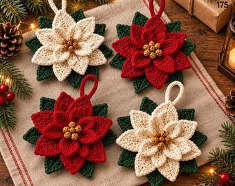 Puede incluir: Cuatro adornos de flor de pascua tejidos a ganchillo con pétalos en capas de color crema y rojo, hojas verde oscuro y centros dorados. Cada flor incluye un pequeño lazo para colgar, dispuestas sobre una superficie de tela beige.