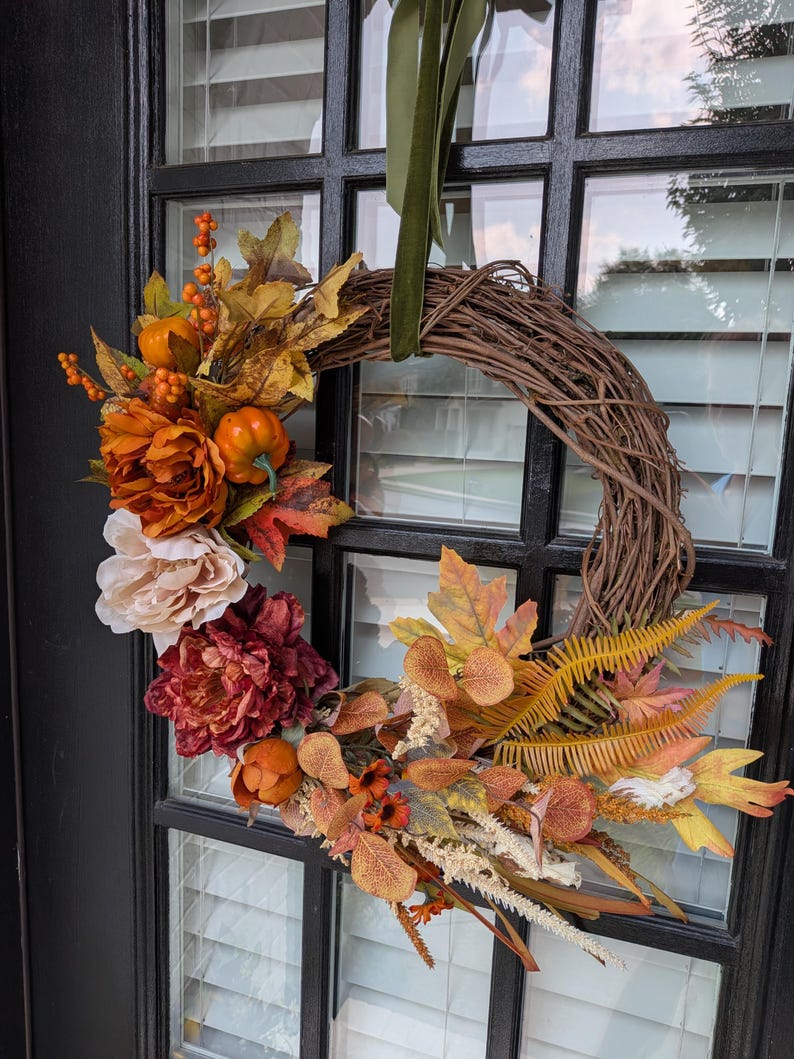 Detail of an autumn grapevine wreath with pumpkins, peonies and maple leaves