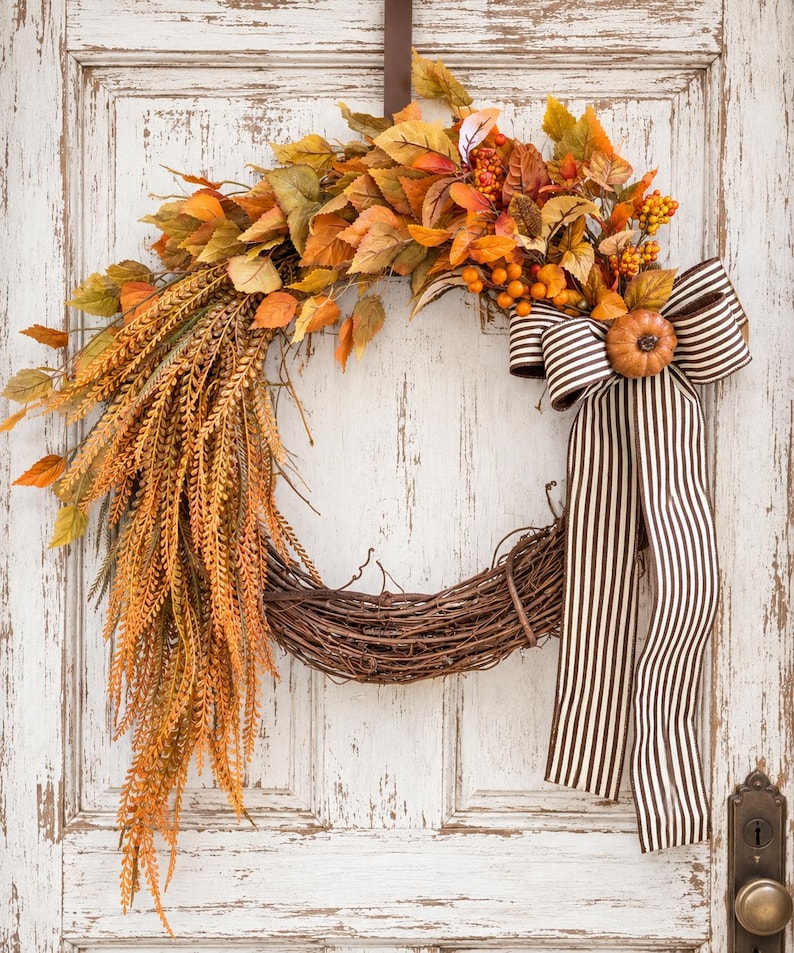 Cascading fall wreath with golden ferns, orange berries and a striped bow