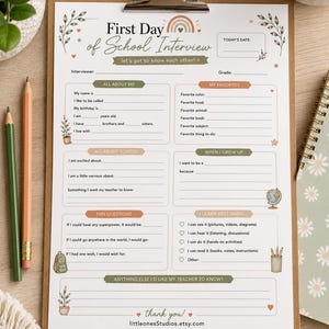 May include: A printed First Day of School Interview questionnaire on a clipboard. The white paper features sections titled All About Me, My Favorites, All About School, When I Grow Up, Fun Questions, and I Learn Best When, decorated with small illustrations.