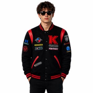 Puede incluir: Una chaqueta universitaria negra con mangas y ribetes de cuero rojo, con cierre de botones a presión, puños acanalados y varios parches bordados que incluyen el texto K, Zenith, Renegade, Zombie, Outsider, Playma, Kavinsky, Horizon, Pulsar y Cameo.