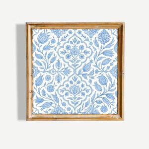 May include: A square wall art piece featuring a light blue and white floral pattern enclosed in a wooden frame. The design displays symmetrical botanical motifs, including stylized tulips, leaves, and blossoms arranged in a repeating pattern.