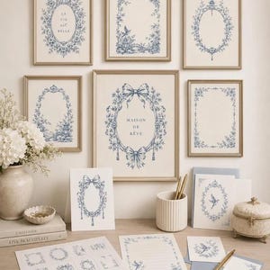 Pu&ograve; includere: Una collezione di stampe da parete e articoli di cancelleria con motivi floreali blu e bianchi in stile toile de Jouy. Le stampe includono il testo LA VIE est BELLE e MAISON DE R&Ecirc;VE, insieme a varie cornici ovali e rettangolari con motivi botanici.